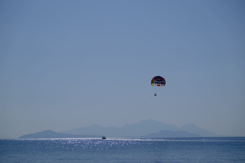 23 October 2020, Greece, Kefalos: Tourists hang on a parasailing parachute and let themselves be towed by a boat across the sea at Kefalos off the island of Kos in Greece. Photo: Robert Michael/dpa-Zentralbild/ZB
